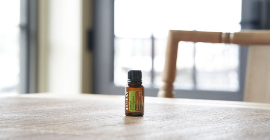 Lemongrass oil for insect repellent in einer Glasflasche mit frischen Zitronengrasstängeln auf einem Holztisch