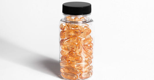 Eine Flasche pränatale Vitamine mit DHA-Kapseln auf einem hellen Holztisch, daneben eine Omega-3-Fischölkapsel.
