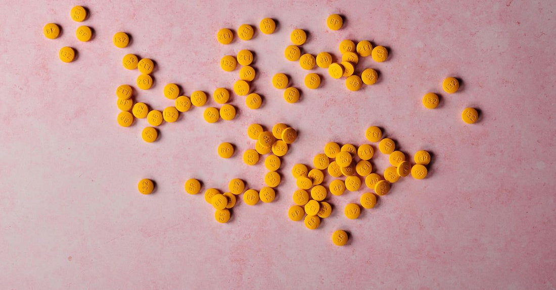 Nahaufnahme von B-Complex-Vitaminkapseln und einer geöffneten Dose auf einem hellen Holztisch – b-complex buying guide.