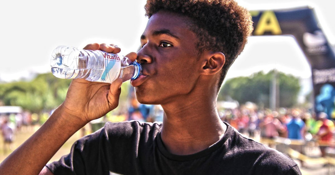Sports Drink vs Water for Hydration: Zwei Flaschen – eine mit klarem Wasser, eine mit blauem Sportgetränk – nebeneinander auf einem Holztisch nach dem Training.