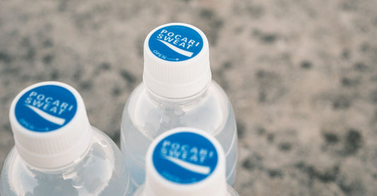 Hydration Powder for Hangover: Ein Glas mit aufgelöstem Elektrolytpulver und ein Messlöffel auf einem weißen Tisch.