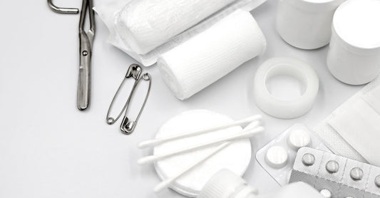 Best Erste Hilfe 2026 Set flach auf hellem Hintergrund mit Verbandsmaterial und Schere