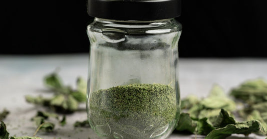 Ein Glas mit feinem Psyllium Husk Pulver und ein Messlöffel auf einer hellen Holzoberfläche – natürliche Ballaststoffquelle für die Verdauung bei Verstopfung.