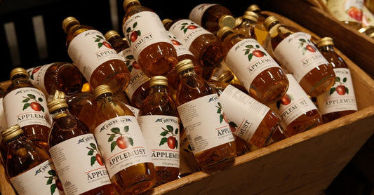 Nahaufnahme einer geöffneten Flasche mit Apfelessig-Kapseln auf einem Holztisch, daneben ein Glas Wasser und ein grüner Apfel. Veranschaulicht die einfache Integration von Apfelessig-Kapseln in die tägliche Routine.