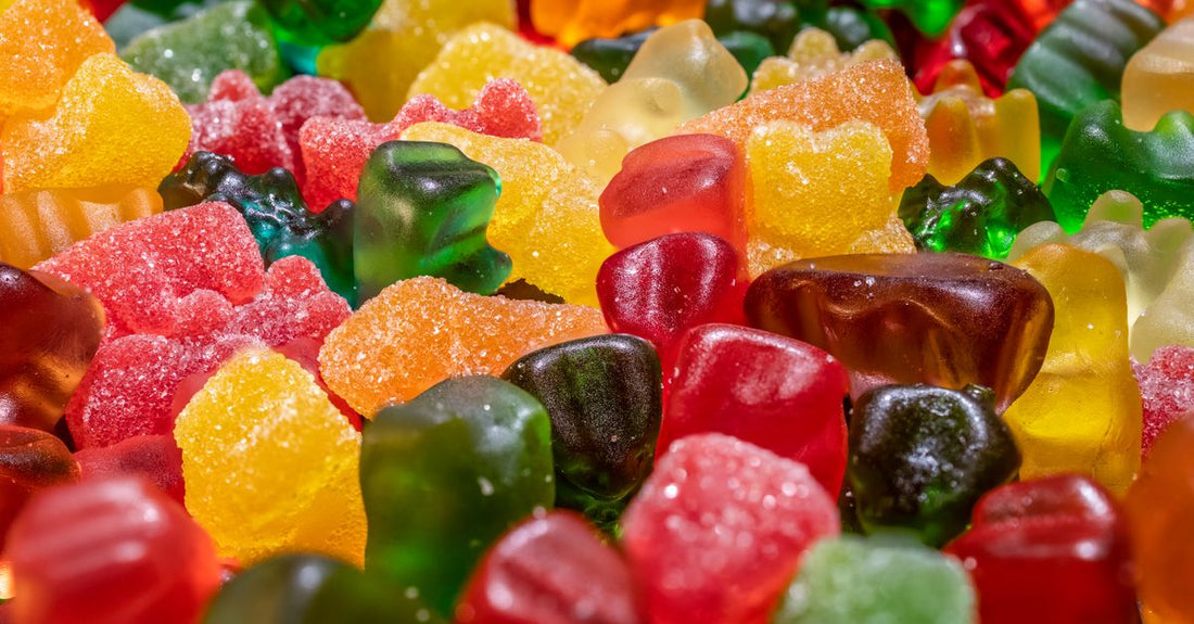 Bunte Flasche mit besten Kinder-Vitaminen 2026 als Gummibärchen, umgeben von frischem Obst auf hellem Hintergrund