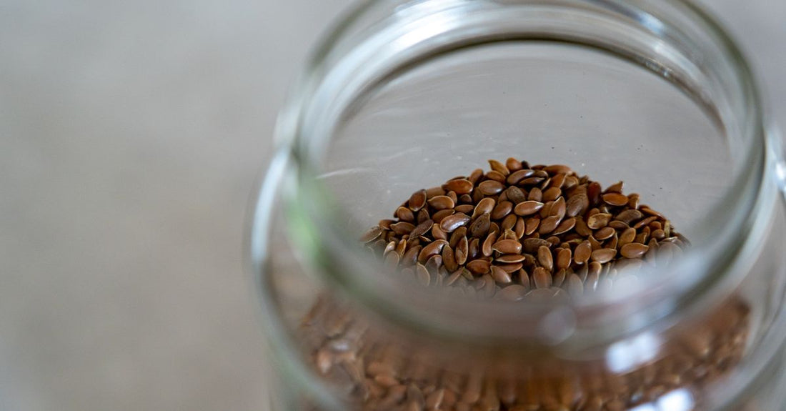 Geöffnetes Glas mit fein gemahlenen Flohsamenschalen auf einem Holztisch, daneben ein Messlöffel – Flohsamenschalen Buying Guide