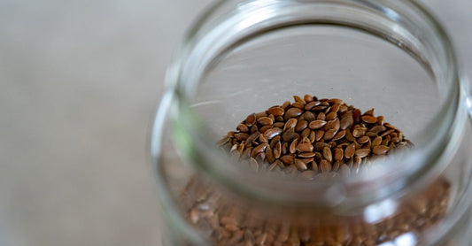 Geöffnetes Glas mit fein gemahlenen Flohsamenschalen auf einem Holztisch, daneben ein Messlöffel – Flohsamenschalen Buying Guide