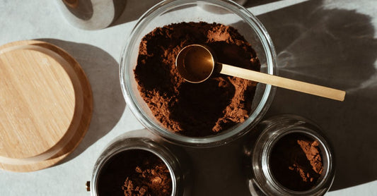 Proteinpulver zum Abnehmen: Ein Messlöffel mit Whey-Proteinpulver neben einem Glas Shake auf einer hellen Küchenarbeitsplatte
