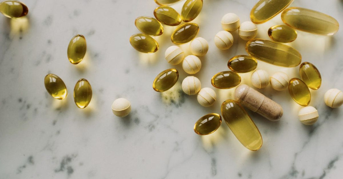 Eine Flasche Vitamin-D-Kapseln auf einem weißen Tisch, daneben ein Glas Wasser.