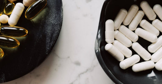 Nahaufnahme von Nahrungsergänzungsmitteln in Kapselform auf einem hellen Holztisch – beste Gesundheitsvorsorge 2026