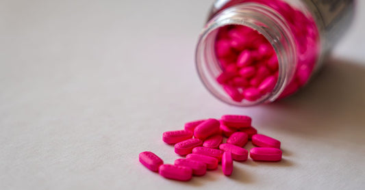 Nahaufnahme von Cranberry-Kapseln und getrockneten Cranberries auf hellem Holz – how to choose cranberry für beste Harnwegsgesundheit.