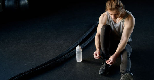 Best Pre Workout for Women 2026: Pulverdose mit Trainingsbooster neben einem Shaker auf einer Fitnessmatte
