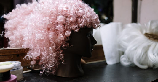 Eine blonde Echthaarperücke mit Lace-Front auf einem Perückenständer vor neutralem Hintergrund