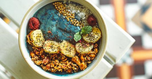 Chlorella- und Spirulina-Pulver in einer Schüssel, umgeben von frischen grünen Blättern – Chlorella Spirulina Benefits für Ihre Gesundheit