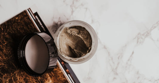 Sleeping Masks Buying Guide: Ein Glas-Tiegel mit Nachtmaske auf Marmoruntergrund, umgeben von Hautpflege-Zubehör