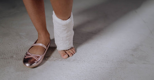 Eine Sprunggelenkbandage liegt auf einer Yogamatte neben einem Paar Laufschuhen und einer Wasserflasche – die beste Sprunggelenkstütze für Sport im Einsatz.