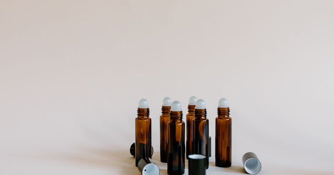Nahaufnahme einer Roller Bottle für ätherische Öle mit Edelstahlkugel und duftender Flüssigkeit auf weißem Hintergrund.