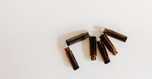 Mehrere hochwertige Glas-Roller-Bottles in verschiedenen Farben auf einer Holzoberfläche, ideal für die gezielte Anwendung ätherischer Öle.