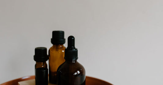 Verschiedene Flaschen mit Trägerölen wie Jojoba-, Mandel- und Kokosöl auf einem Holztisch – how to choose carrier oils