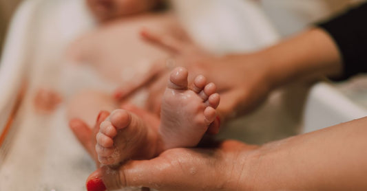 Eine Flasche baby bubble bath safe for newborns auf einem Holztisch im Badezimmer, umgeben von weichen Handtüchern.