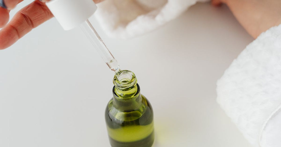 Eine Flasche Sodium PCA Feuchtigkeitsspray auf einem weißen Marmortisch, umgeben von grünen Aloe-Vera-Blättern – Best Sodium 2026.