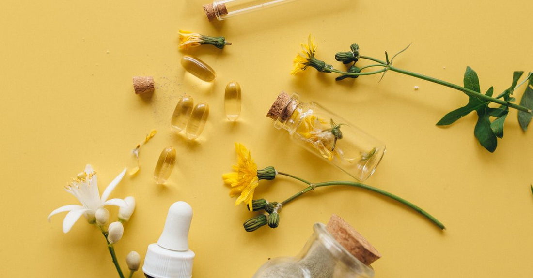 Eine Flasche mit liver detox supplements auf einem Holztisch neben Mariendistelblüten und einem Glas Wasser.