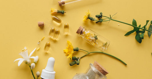 Eine Flasche mit liver detox supplements auf einem Holztisch neben Mariendistelblüten und einem Glas Wasser.