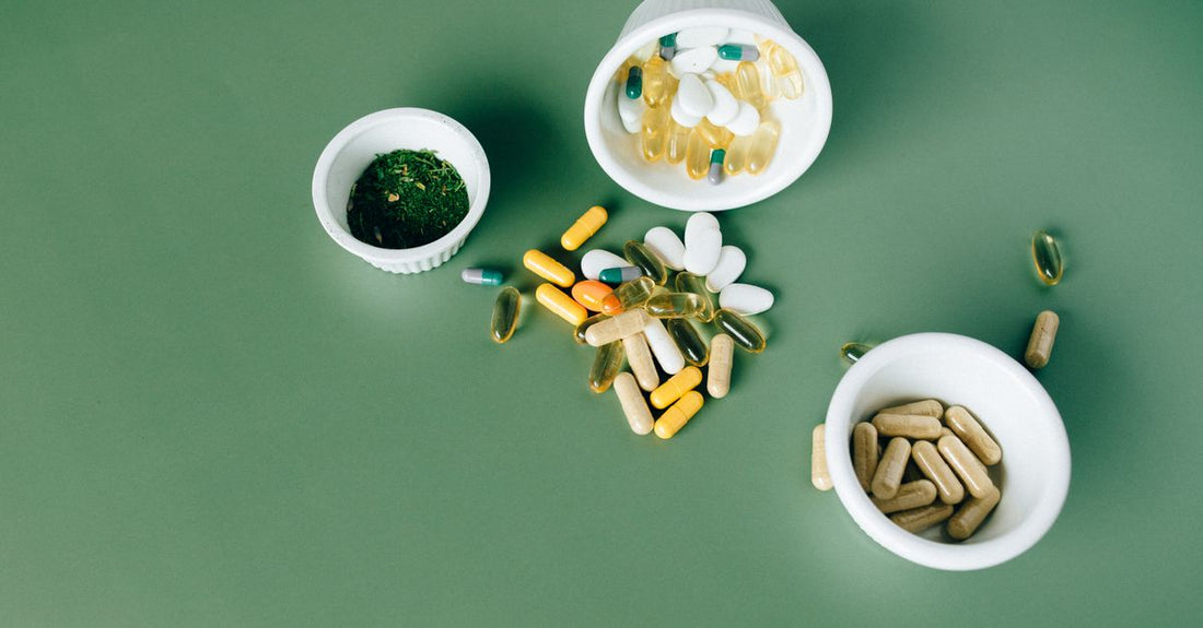 Flache Lage von Prenatal-Vitamin-Kapseln und einem Glas Wasser auf einem hellen Holztisch – Symbol für die tägliche Routine und mögliche Nebenwirkungen wie Übelkeit