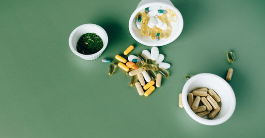 Flache Lage von Prenatal-Vitamin-Kapseln und einem Glas Wasser auf einem hellen Holztisch – Symbol für die tägliche Routine und mögliche Nebenwirkungen wie Übelkeit