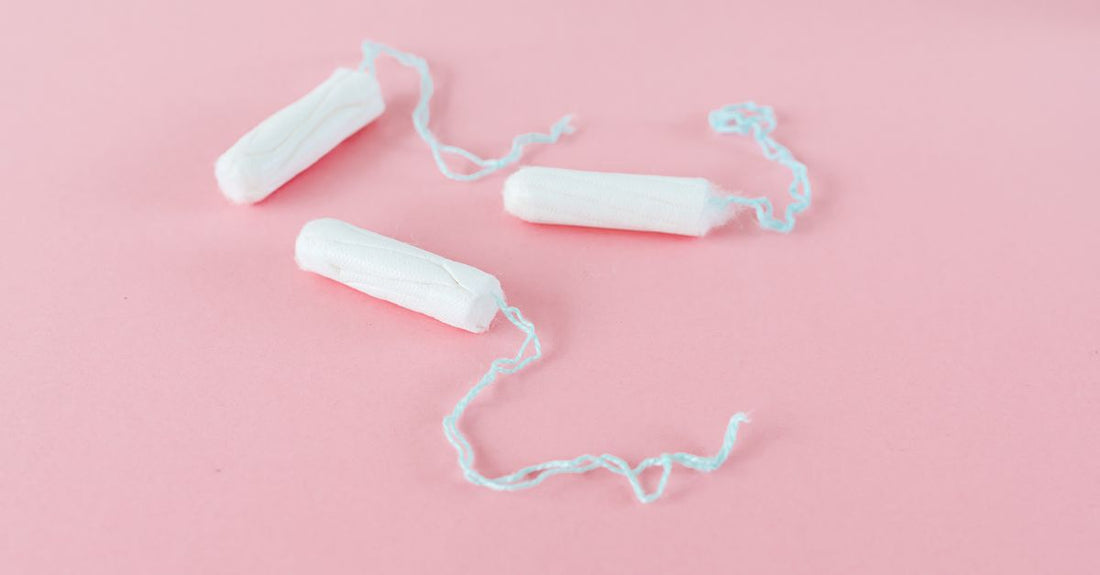 Eine Packung Bio-Baumwolltampons auf einem weißen Hintergrund, daneben eine einzelne Tampon mit Applikator