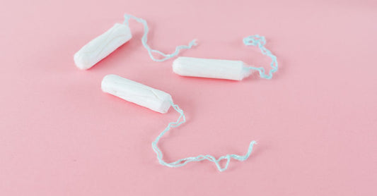Eine Packung Bio-Baumwolltampons auf einem weißen Hintergrund, daneben eine einzelne Tampon mit Applikator