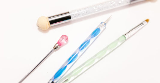 Nahaufnahme eines Sets bester Nail Art Pinsel 2026, ordentlich auf einer weißen Fläche angeordnet, darunter feine Detailpinsel und Schrägpinsel.