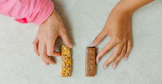 Verschiedene Energie- und Proteinriegel auf einem hellen Holztisch, hilfreich beim Energie- & Proteinriegel wählen.