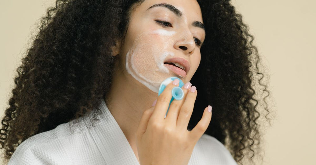 Eine moderne elektrische Gesichtsreinigungsbürste mit Silikonborsten liegt auf einem hellen Marmoruntergrund – powered facial cleansing brushes & devices buying guide